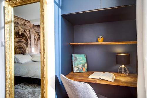 a mirror reflecting a bedroom with a desk and a bed at La Suite du Roi Henri in Vendôme