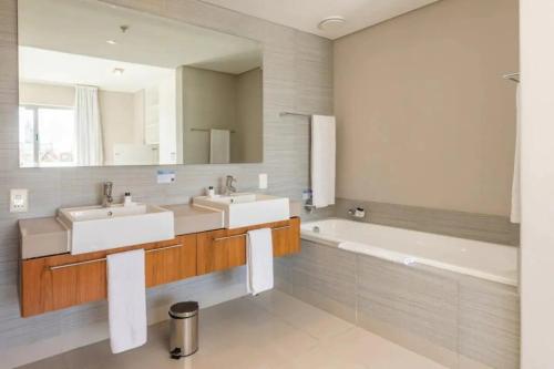 a bathroom with two sinks and a tub and a mirror at Harbour Bridge 33C in Cape Town