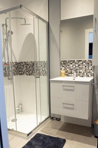 une salle de bain blanche avec une douche et un lavabo dans l'établissement Le 73 Chambéry, à Chambéry