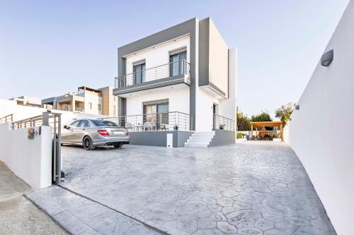 a white house with a car parked in a driveway at Ramo Luxury Villa in Kremasti