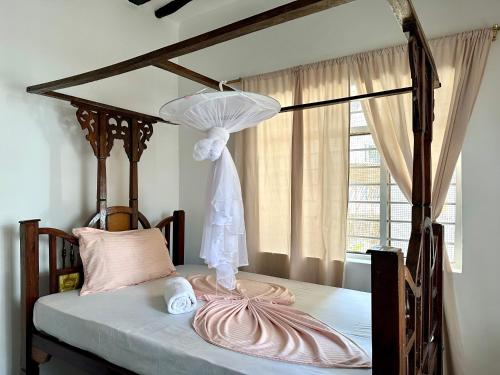 a bedroom with a canopy bed and a window at Mlango Paje House II in Paje