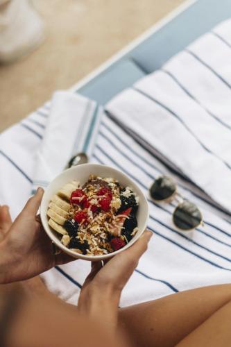 a person holding a bowl of cereal and fruit at St. Regis Bahia Beach Resort, Puerto Rico in Rio Grande