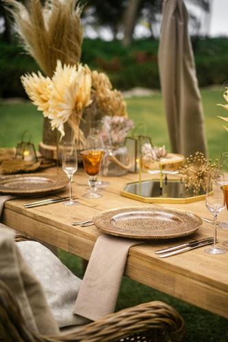 a wooden table with plates and wine glasses on it at St. Regis Bahia Beach Resort, Puerto Rico in Rio Grande
