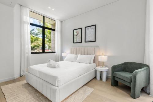 a white bedroom with a bed and a chair at Perfect Vacation Home w Terrace & Private Garage in Sydney