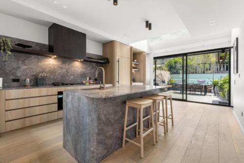 an open kitchen with a large concrete island with bar stools at Perfect Vacation Home w Terrace & Private Garage in Sydney