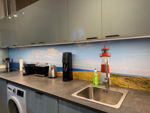 a kitchen sink with a painting of a lighthouse at Gästehaus Weserblick am Weser-Sandstrand in Berne