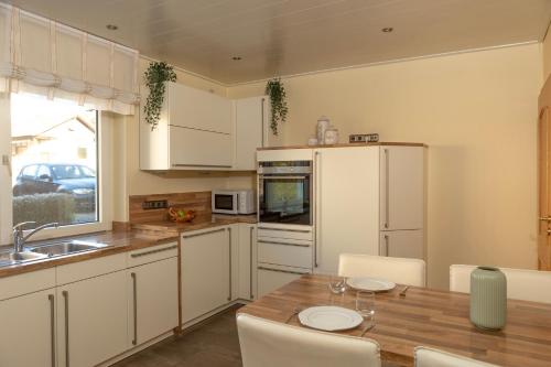 a kitchen with a wooden table and white cabinets at Ferienwohnung MiA in Frankenau