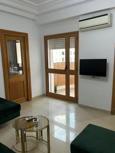 a living room with a couch and a table and a tv at Lumineux Calme avec Parking Privé Proche La Marsa in Tunis