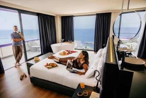 a woman laying on a bed in a hotel room at Hard Rock Hotel Tenerife in Adeje