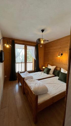 une chambre avec deux lits et une grande fenêtre dans l'établissement Chalet Soleil, à La Rosière
