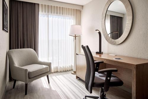a room with a desk and a chair and a mirror at Sheraton Richmond Airport Hotel in Sandston