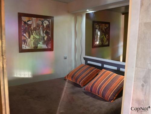 - un lit dans une chambre avec 2 photos sur le mur dans l'établissement CapNat - Village Naturiste - Port Nature - Villa Marrakech, au Cap d'Agde