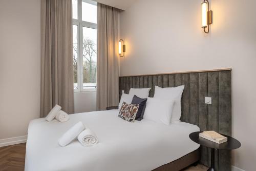 a bedroom with a large white bed and a window at L'Horloge - Appart'Hotel proche de Disneyland in Montévrain