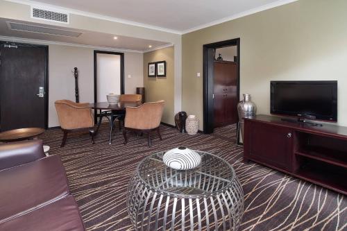 a living room with a table and a flat screen tv at Protea Hotel by Marriott Blantyre Ryalls in Blantyre