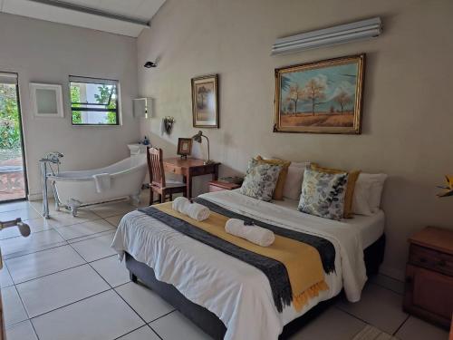 a bedroom with a large bed and a bath tub at Tzaneen White House Lodge in Tzaneen