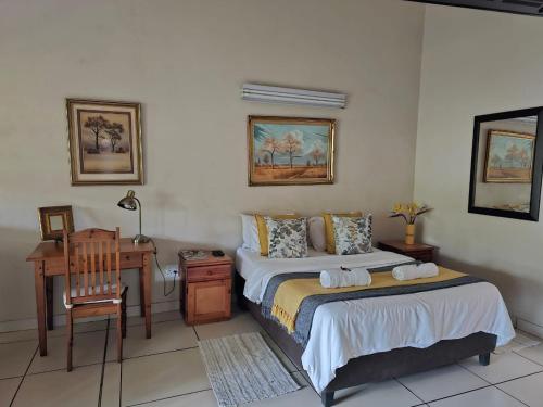 a bedroom with two beds and a desk and a table at Tzaneen White House Lodge in Tzaneen
