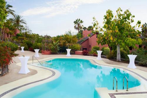 a pool at a resort with blue water and trees at The Ritz-Carlton Tenerife, Abama in Guía de Isora