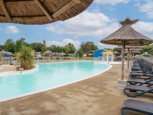- une piscine avec des chaises longues et un parasol dans l'établissement Domaine Résidentiel de Plein Air Le Vorlen, à Fouesnant