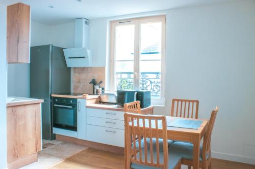 a kitchen with a table and a table and a table and chairs at 2P refait à neuf, calme, quartier historique, entre seine et cathédrale in Mantes-la-Jolie