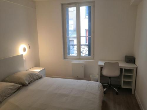 a bedroom with a bed and a desk and a window at 2P refait à neuf, calme, quartier historique, entre seine et cathédrale in Mantes-la-Jolie
