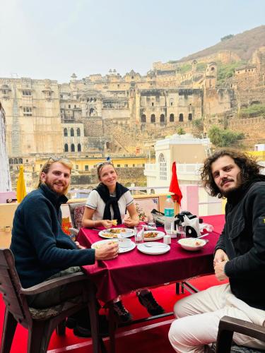 a group of people sitting at a table in front of the coliseum at The Palace View Homestay & Restaurant in Būndi