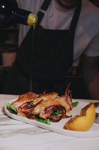 a person is drizzling sauce on a plate of food at Yazz Collective in Fethiye