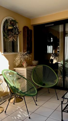 deux chaises vertes assises dans une pièce dans l'établissement Appart CANNES résidence piscine-parc-tennis, à Cannes