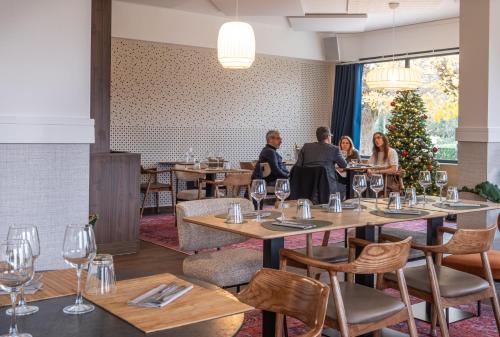 people sitting at tables in a restaurant with a christmas tree at La Coudraie - Proche de Disneyland in Montévrain