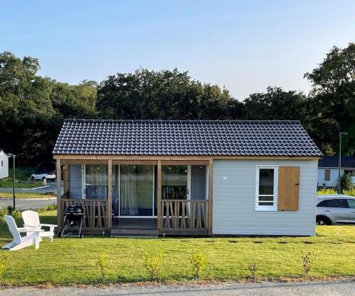 a tiny house with a porch and a white chair at Chalet familial avec piscine-Finistère Sud in Pont-lʼAbbé