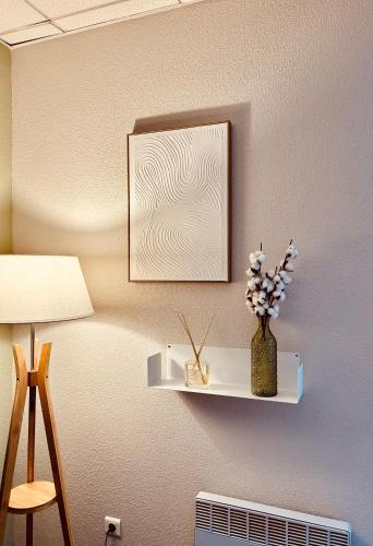 a wall with a shelf with a vase of flowers at Résidence Le Grand Tétras- SPA THERMAL INCLUS in Ax-les-Thermes