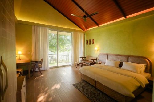 a bedroom with a bed and a desk and a window at Tiki Farms in Karjat