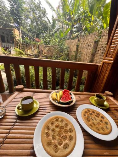 a table with two plates of food and cups of coffee at Coffee Homestay Tetebatu in Tetebatu