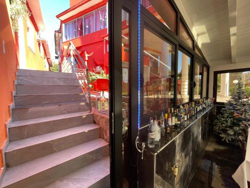 a glass door of a building with a staircase with bottles at Hotel Bar Restaurant Mete in Peshkëpi