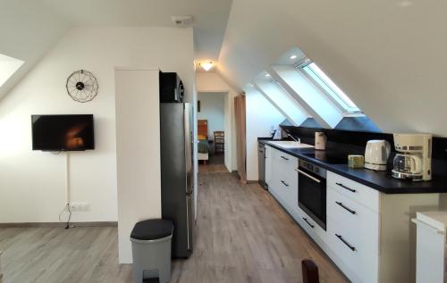 une cuisine avec des armoires blanches et un réfrigérateur noir dans l'établissement Location bretagne Plougasnou LocPalais, à Plougasnou