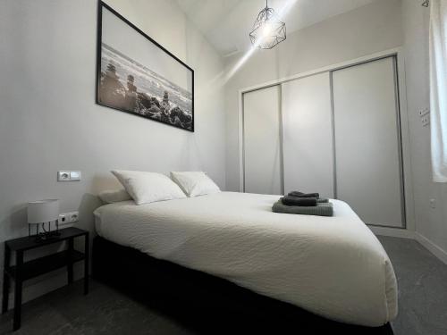 a bedroom with a white bed with a picture on the wall at Kadis-Korazon Grupo AC Gestion in Cádiz