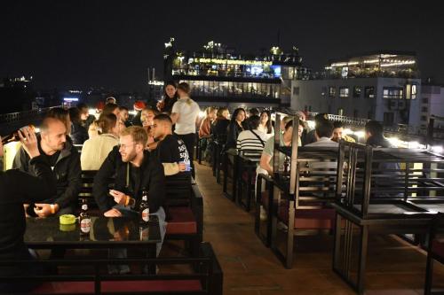 a crowd of people sitting on a roof at night at Lakeview Backpackers Hostel & Rooftop Bar in Hanoi
