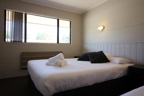 a bedroom with a large bed with towels on it at Snowy Mountains Resort and Function Centre in Adaminaby