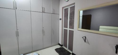 a bathroom with white cabinets and a mirror at Homestay Arysha Dhalia in Kuala Terengganu