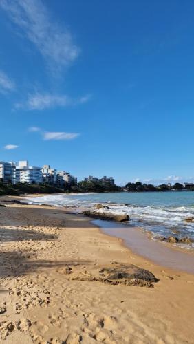 a beach with footprints in the sand and the ocean at Casa do Sol - Nova Guarapari in Guarapari