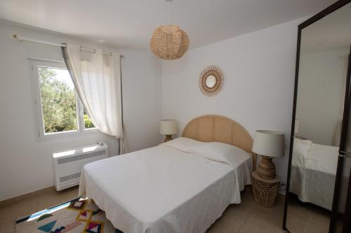 une chambre blanche avec un lit et un miroir dans l'établissement Charmante villa avec piscine proche ville et plage, à Calvi