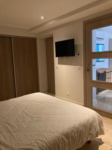 une chambre avec un lit et une télévision au mur dans l'établissement Les ISSAMBRES, à Roquebrune-sur Argens