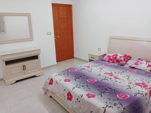 a bedroom with a bed with pink flowers on it at Studio LINA in Hennchir Ksar Rhaleb