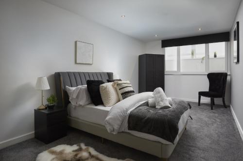 a bedroom with a bed and a chair and a window at Hayy Luxury Homes Near Bradford City Centre in Bradford