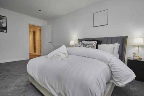a large white bed with white sheets and pillows at Hayy Luxury Homes Near Bradford City Centre in Bradford