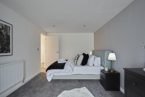 a bedroom with a bed with white sheets and pillows at Hayy Luxury Homes Near Bradford City Centre in Bradford