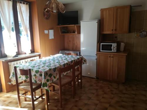a kitchen with a table with chairs and a refrigerator at Appartamento in Val di Sole in Commezzadura