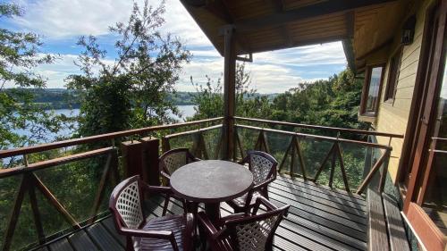 a table and chairs on a porch with a view of the water at Hotel y Cabañas Punta Larga - Caja Los Andes in Frutillar