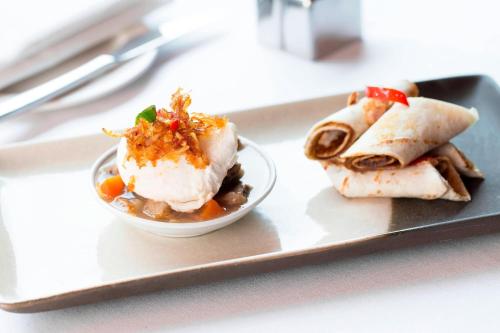 ジャカルタにあるル メリディアン ジャカルタのトレイの上に食べ物の入ったボウルが乗った皿