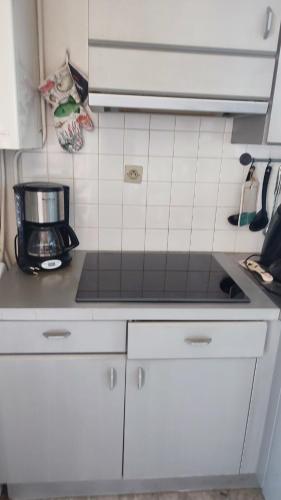 une cuisine avec des armoires blanches et un comptoir dans l'établissement Appartement Climatisé Vue Mer Route des Sanguinaires, à Ajaccio