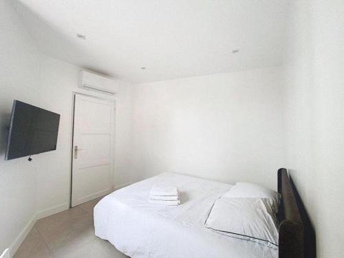 une chambre blanche avec un lit et une télévision à écran plat dans l'établissement Appartement 2 pieces rénové avec clim, Wi-Fi et tout équipé - Proche de rue d'Antibes et Palais des Festivals, à Cannes